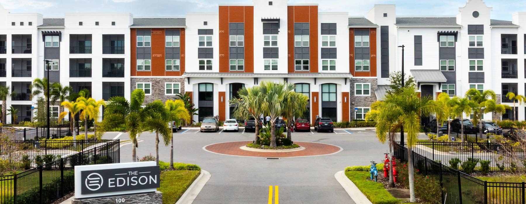 a road with cars and trees by a building