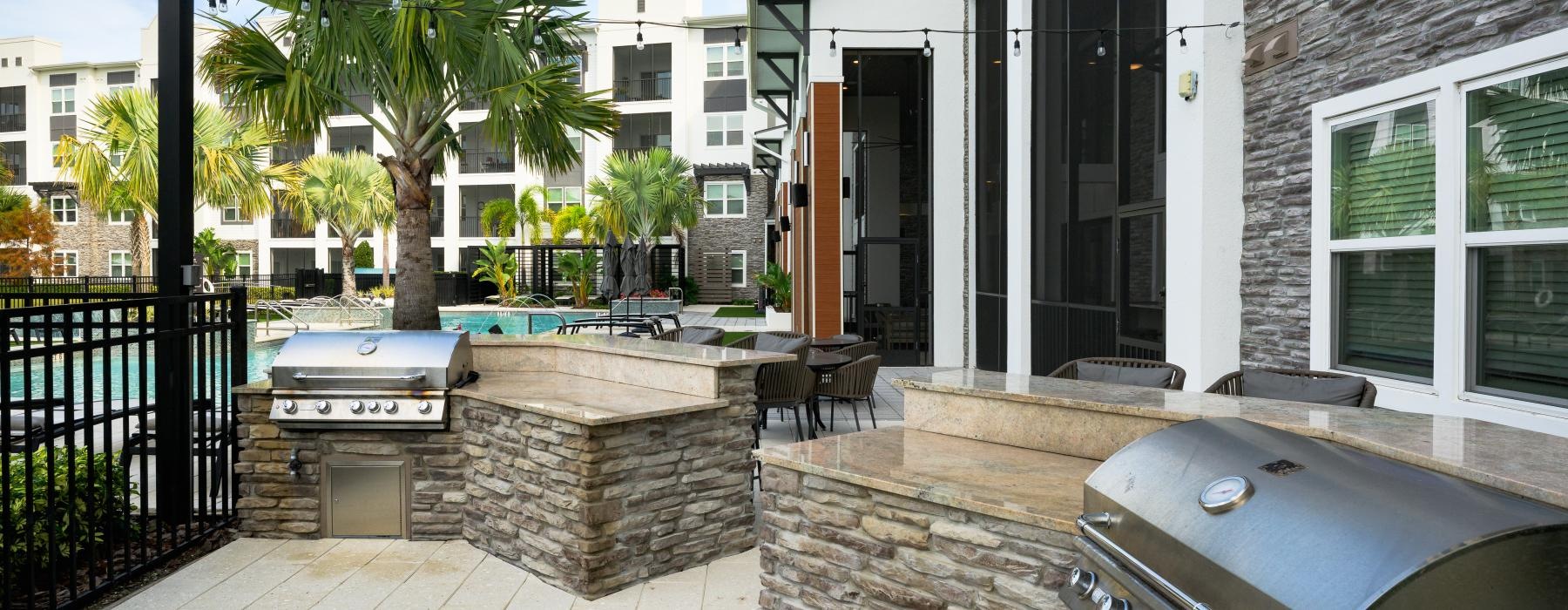 a patio with a grill and a brick wall with a patio and trees